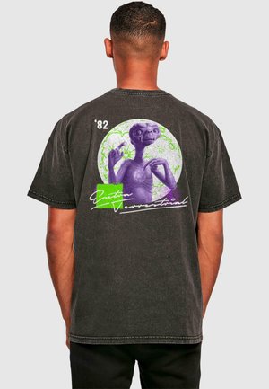 Black cotton t-shirt with a graphic of a purple alien figure, surrounded by green circular patterns, and text reading '82 and "Extra Terrestrial" in white.