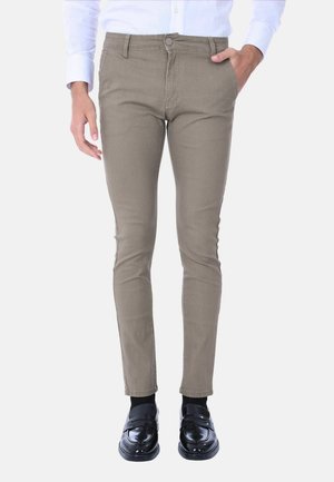 Pantaloni beige slim-fit realizzati in tessuto testurizzato. Presentano una chiusura con bottone e cinque tasche. Abbinati a mocassini neri e calzini neri.