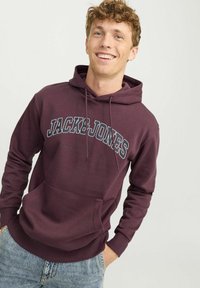 Maroonska dukserica s kapuljačom i vezicama, prednji džep i "JACK & JONES" logo u bijeloj i sivoj boji. Mješavina pamuka, srednje teška tkanina.