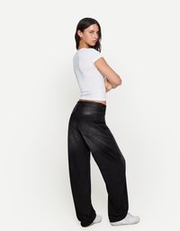Jean large noir avec taille haute, associé à un haut ajusté à manches courtes blanc. Tissu lisse, détails minimaux et design classique.
