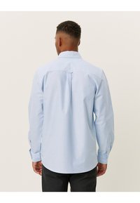 Lichtblauwe blouse met lange mouwen, achterkant met plooidetail en afgeronde zoom. De stof lijkt soepel met een subtiele textuur.