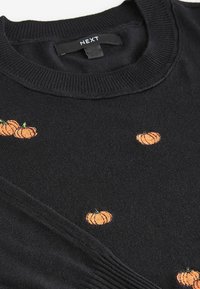 Maglione nero con zucche arancioni ricamate, scollatura a costine e texture liscia. Etichetta "NEXT" visibile vicino al colletto.