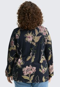 Chemise florale navy à manches longues, ornée de motifs de fleurs roses et vertes, avec une coupe décontractée. Tissu doux avec une finition texturée.
