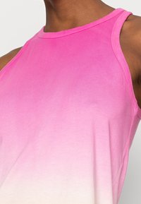 Primo piano di una persona che indossa una canotta senza maniche ombrellata dal rosa al bianco.