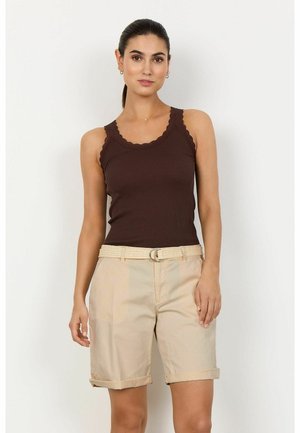 Débardeur marron à côtes avec des bords festonnés, associé à un short beige retroussé ; le short est doté d'une ceinture tressée avec une boucle en métal.