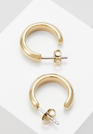 Paire de petites boucles d'oreilles créoles épaisses en or avec tiges métalliques et fermoirs papillon, présentées sur une surface blanche.