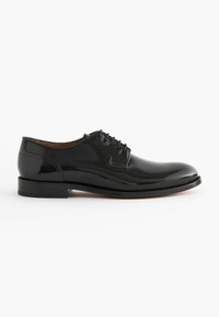 Chaussure de ville en cuir noir avec une finition brillante, bout pointu et design à lacets à six œillets. Semelle plate en caoutchouc avec une adhérence minimale.