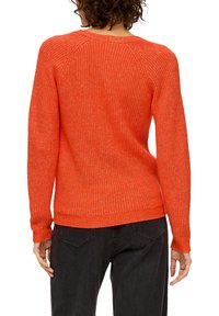 Gebreide oranje trui met een ribbelstructuur, lange mouwen en een ronde hals. Heeft raglanmouwen en een ontspannen pasvorm.