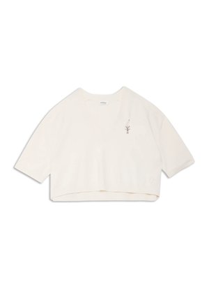 Haut court en maille écru avec manches jusqu'au coude et petite broderie délicate sur le haut du côté gauche de la poitrine.