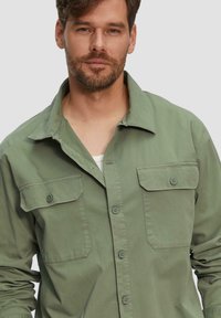 Lichtgroene button-up shirt met twee borstzakken, een gespreide kraag en een relaxed fit. Gemaakt van katoen. Zichtbare knopen en stikdetails.