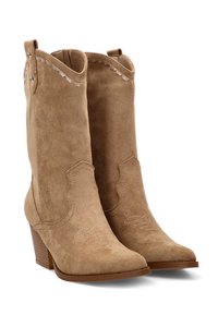 Botas de vaquero de ante en color beige con punta afilada y tacón apilado. Presentan costuras decorativas en el caño y tiradores para ponérselas fácilmente.