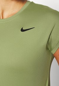 Camisa deportiva de manga corta de color verde oliva con una textura acanalada y un logotipo negro de Nike en la parte superior izquierda del pecho.