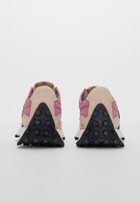 Sneakers med en övre del i rosa och beige mocka, svarta accenter och en strukturerad svart gummisula, med en triangulär häldesign.