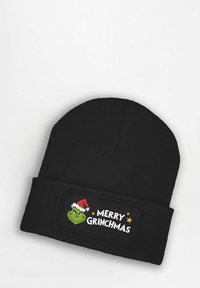 Black knit beanie featuring a patch with a green character in a red Santa hat, text “MERRY GRINCHMAS,” and gold star accents.