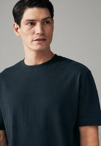 Donker marineblauw katoenen t-shirt met een ronde hals, korte mouwen en een gladde, effen textuur zonder zichtbare patronen of accenten.