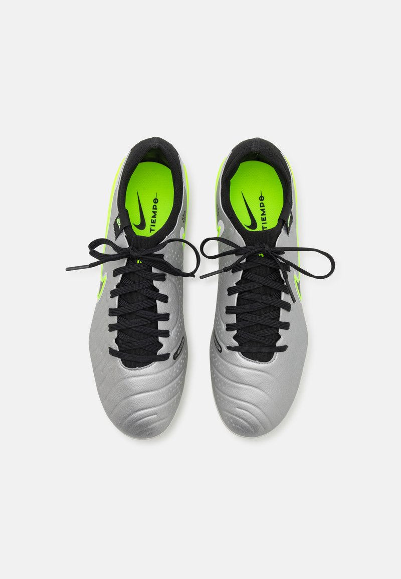 Des crampons de football gris avec des lacets noirs, présentant une tige texturée et de vives accents vert néon sur le talon et la semelle intérieure.