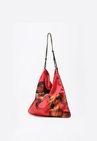 Czerwona torba wykonana z materiału, o trójkątnym kształcie, z długimi czarnymi paskami i nadrukowanym wzorem dwóch jamników po jednej stronie. Gładka tekstura.