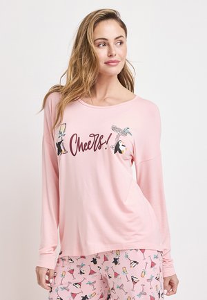 Rosa Langarmoberteil mit einem grafischen Druck von Pinguinen und dem Wort "Prost!" auf der Vorderseite. Kombiniert mit passenden rosa gemusterten Schlafanzughosen.
