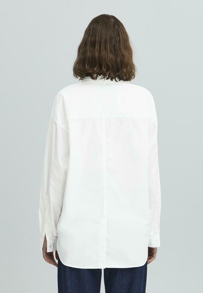 Balta ilgomis rankovėmis marškiniai, su sagomis, laisvas kirpimas, nugaroje klostė, rankogaliai su sagomis, glotni medvilnės tekstūra.