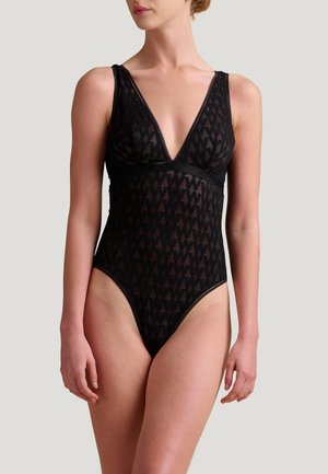 Sort bodysuit med dyb V-udskæring, der har et geometrisk mønster, tekstureret stof og tynde stropper. Højt skårne benåbninger fremhæver designet.