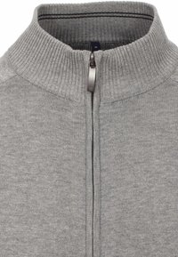 Maglione grigio con zip, dotato di colletto e polsini a coste, caratterizzato da una texture liscia e una cerniera in metallo. Dettaglio a righe all'interno del colletto.