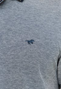 Szary polo z teksturowanej tkaniny, z małym haftowanym logo konia w ciemniejszym odcieniu szarości po lewej stronie klatki piersiowej. Kołnierz ma kontrastowe akcenty.