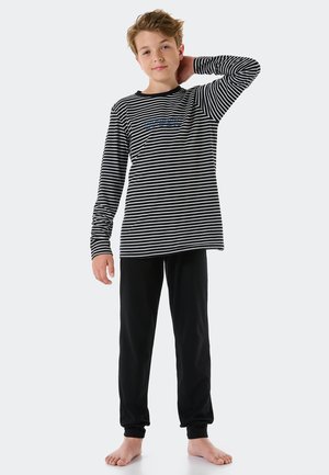 Stribet langærmet bluse i sort og hvid med rund halsudskæring, parret med ensfarvede sorte bukser med elastiske manchetter, lavet af blødt stof.