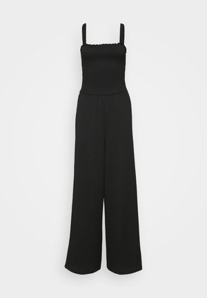 Svart jumpsuit med strikket bodice, firkantet utringning og vide ben. Har elastiske stropper og en teksturert stoff.