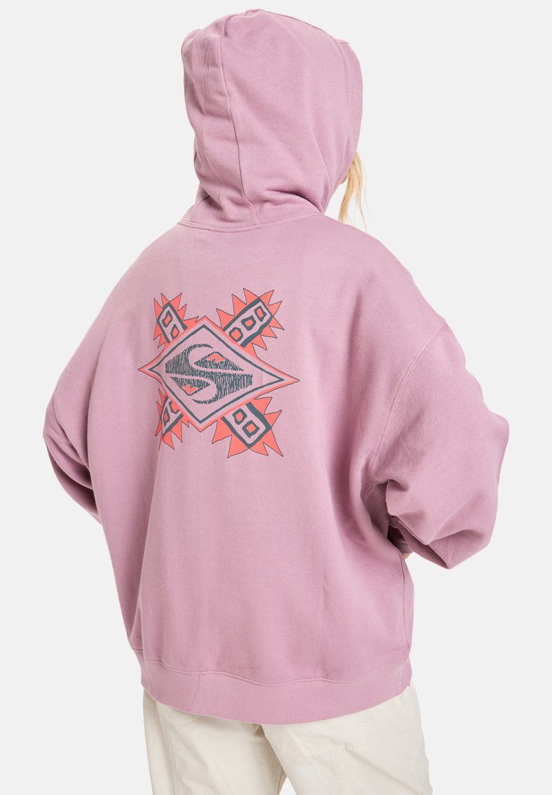 Prečo veľká ružová mikina s predným vreckom a geometrickým grafikou v červenej a šedej farbe na chrbte. Mäkká, textúrovaná tkanina a dizajn s kapucňou.