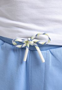 Lichtblauwe sweatpants met een elastische tailleband, voorzien van een meerkleurige koord dat in een strik is gebonden. Zachte stof met een zichtbare textuur.