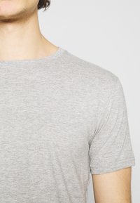 Camiseta de manga corta gris con un diseño clásico de cuello redondo, hecha de una suave y ligera tela con una sutil textura jaspeada.