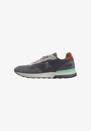 Zapatillas de hombre en gris oscuro, fabricadas con material de ante y textil, con un logo de calavera y huesos cruzados, y detalles en verde menta en la suela.