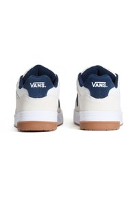 Białe i granatowe zamszowe trampki z brązową gumową podeszwą. Posiadają wyściełany kołnierz oraz logo "VANS" na pięcie i języku.