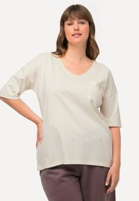 Creme V-hals T-shirt i blød bomuldsblanding med korte ærmer, der har en lille lomme og kontrasterende syninger.