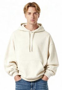 Felpa con cappuccio color crema realizzata in tessuto morbido, con tasca frontale, cappuccio con coulisse e polsini e orlo a coste, abbinata a jeans blu.