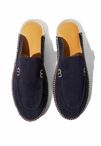 Moccasines de ante azul marino con suela de yute natural, que presentan detalles cosidos y una plantilla de cuero suave. Sin parte trasera para un fácil uso a modo de deslizamiento.