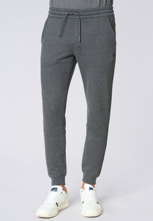Pantaloni jogger grigi in cotone con vita elasticizzata e coulisse. Presentano tasche laterali e polsini a coste. Abbinati a sneakers bianche.