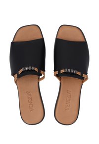 Zwarte synthetische slip-on sandalen met een open teen, tan kleurige binnenzolen en een decoratieve kettingaccent met metalen stenen. Plat zool ontwerp.