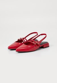 Scarpe slingback in vernice rossa con punta affusolata, dettaglio a doppia fascia e piccoli tacchi a blocco. Texture liscia con finitura lucida.