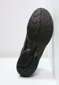 Suola di scarpa in gomma nera con una superficie texturizzata caratterizzata da modelli a onda e logo Ecco. Le scanalature profonde offrono aderenza e trazione.