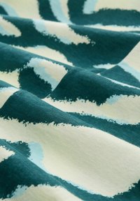 Tissu en coton avec un motif ondulé dans des teintes de bleu canard, bleu clair et crème, créant un aspect texturé et doux.