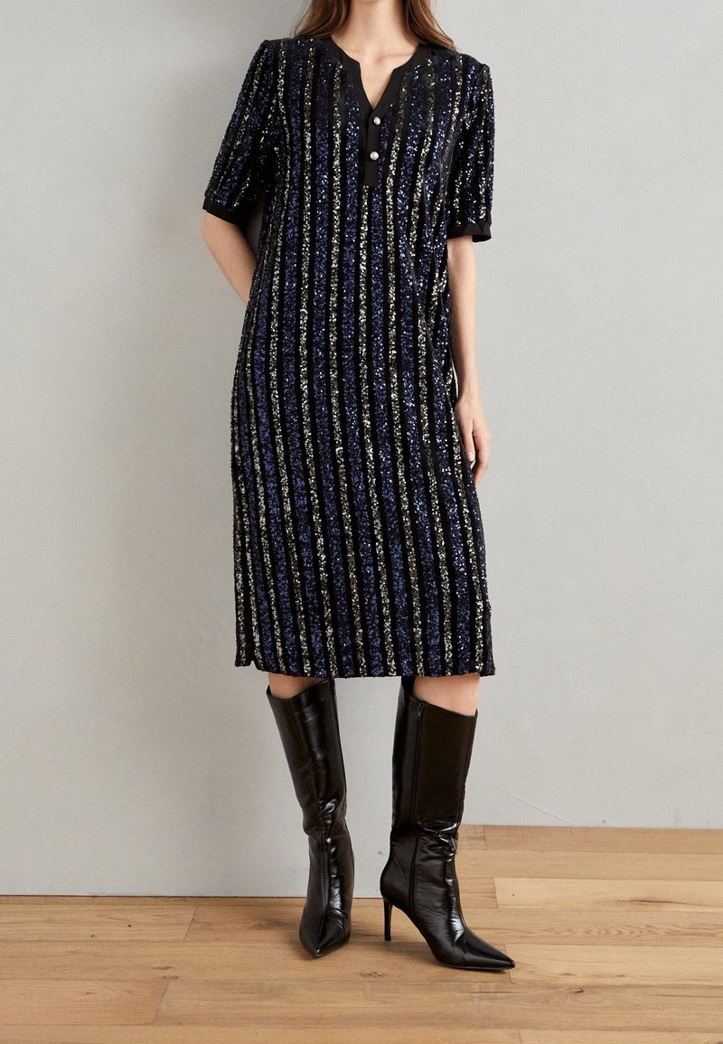 Svart midiklänning med vertikala blå och silverfärgade paljetter, v-ringning, korta ärmar och en knappdetalj vid halslinningen.