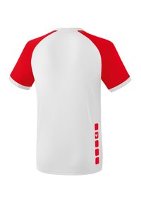 T-shirt a maniche corte con maniche raglan rosse, corpo bianco, scollo rotondo e dettagli rossi a motivo lungo il lato sinistro.