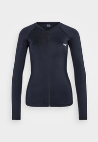 Maglia a maniche lunghe con zip di colore blu navy, realizzata in un tessuto liscio e elastico; presenta maniche raglan e un piccolo logo bianco sul petto.