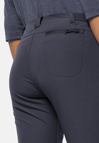 Byxor i mörkgrått tyg, med en bakficka och en mjuk yta. Midjebandet har en dragsko för justerbar passform.