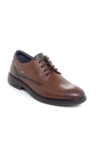 Zapato de cuero marrón con cordones y punta redondeada, forro texturizado y detalles negros en el talón y los cordones. Presenta una robusta suela de goma.