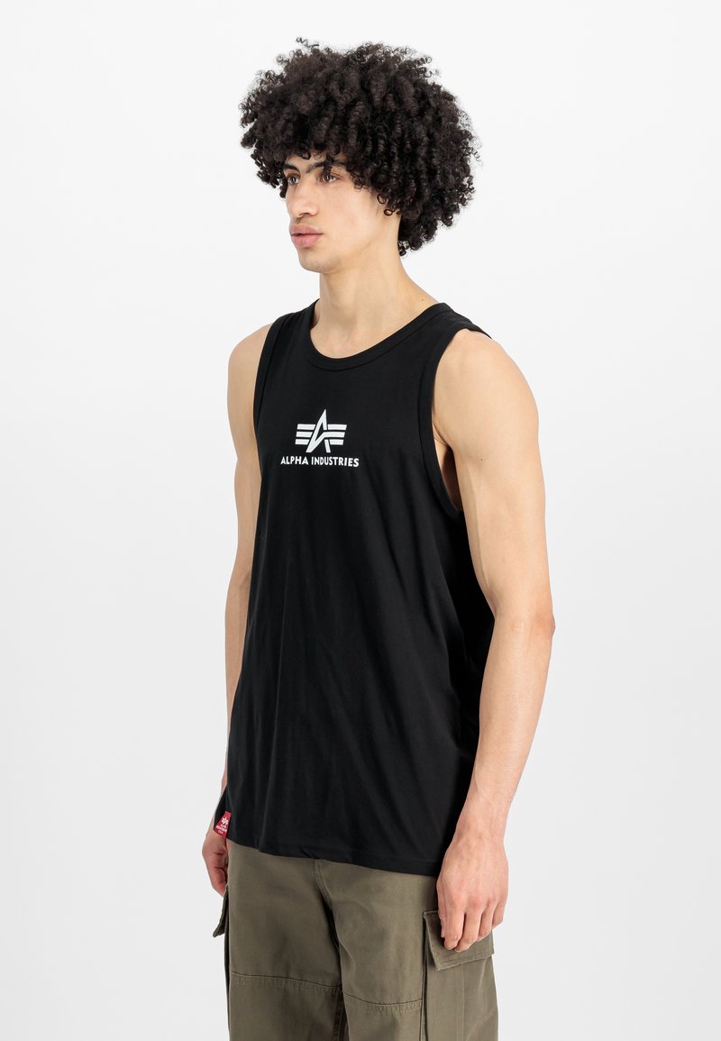 Μαύρο αμάνικο μπλουζάκι φτιαγμένο από βαμβάκι. Διαθέτει λευκό λογότυπο "ALPHA INDUSTRIES" στο στήθος. Απλός σχεδιασμός με στρογγυλή λαιμόκοψη.