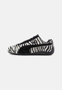 Black and white zebra-striped sneakers with suede and leather materials, featuring a low profile, laces, and rubber sole.