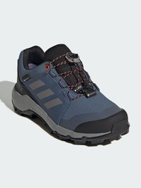 Chaussure de randonnée grise avec un dessus en tissu texturé, capuchon en caoutchouc noir à l'avant, accents orange et un système de laçage rapide pour un ajustement sécurisé.