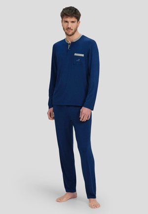 Conjunto de pijama azul marino en un material suave, con mangas largas, un bolsillo con un acento gris claro y un diseño de cuello redondo.